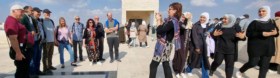 Group of people having their photo taken with young women students watching curiously